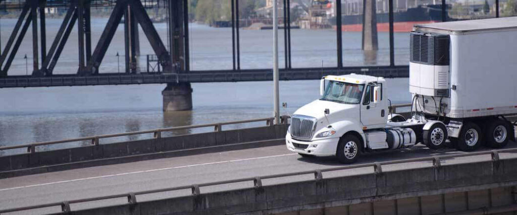 A chilled freight services semi truck driving across a bridge