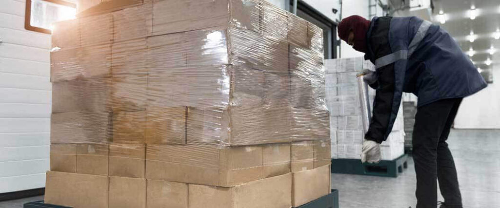 A cold chain food distribution worker checking the length of a palletized shipment