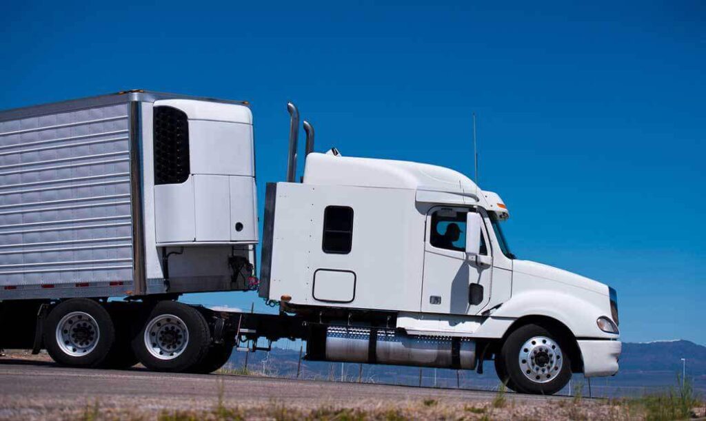 Side view of a semi truck with the front of a reefer trailer visible