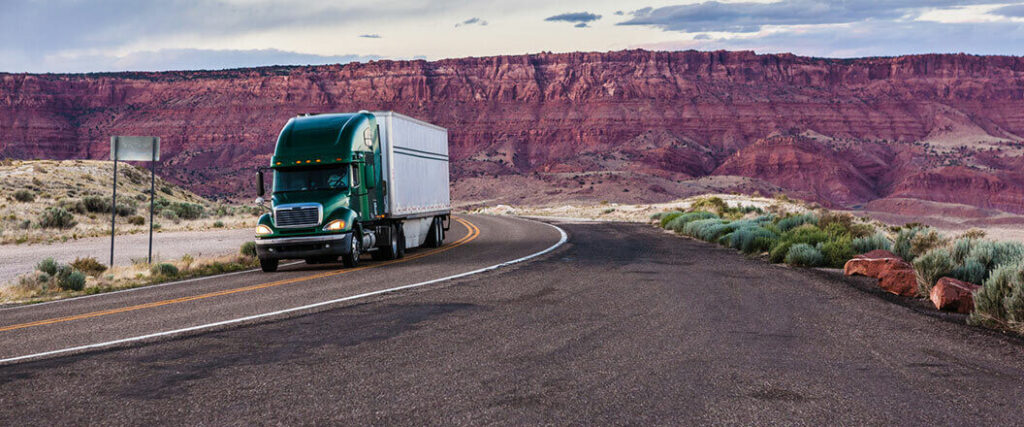 A semi truck traveling down a desert highway.